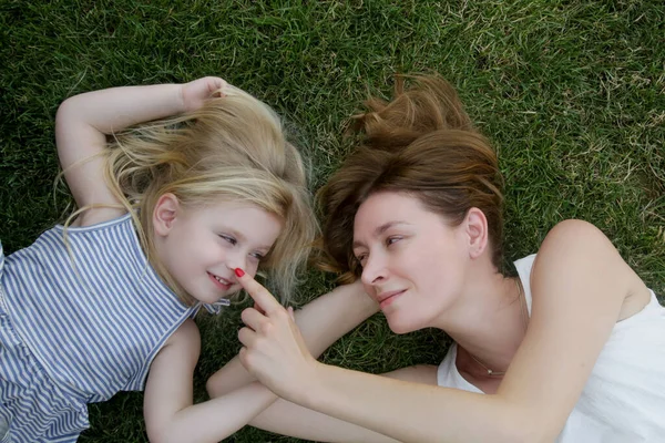 Anne ve kızı çimlerin üzerinde yatıyor, yaz boyunca doğada vakit geçiriyorlar.