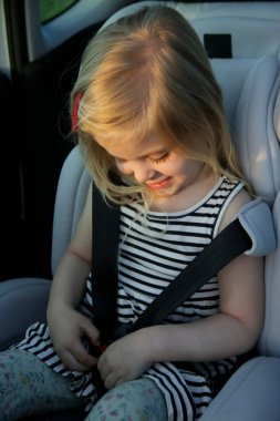 Tatlı küçük kız emniyet kemerini emniyet oto koltuğuna takıyor.
