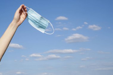 Coronavirus bitti. Karantina ve Corona Virüsü salgınının sonu. Kadın kalkıyor ve tıbbi koruyucu maskeyi atıyor. Coronavirüs salgınından sonra hayatın ve temiz havanın tadını çıkarıyorum..