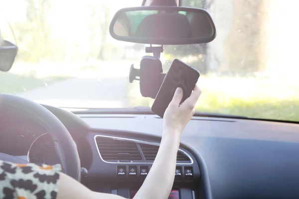 車の電話ホルダーに携帯電話を挿入する女性 — ストック写真