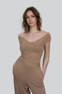 Organik pamuk ve temel pantolonlardan kolsuz bluz giyip bej rengi elbiseler giyen kadın modelin seri fotoğrafları..