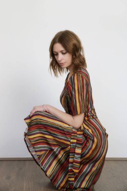 Acayip renkli çizgili bir elbise giymiş bir kadın. Stüdyo çekimi.