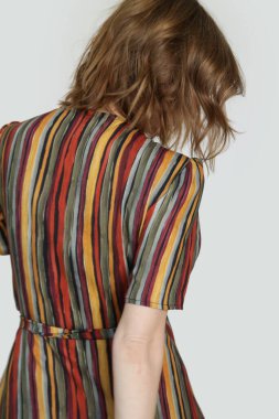 Acayip renkli çizgili bir elbise giymiş bir kadın. Stüdyo çekimi.