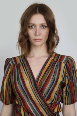 Acayip renkli çizgili bir elbise giymiş bir kadın. Stüdyo çekimi.