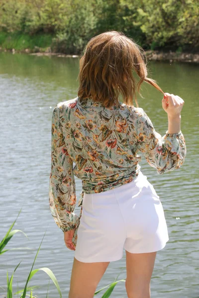 穿着花衬衫和白短裤的女人在大自然中享受着阳光灿烂的日子 — 图库照片