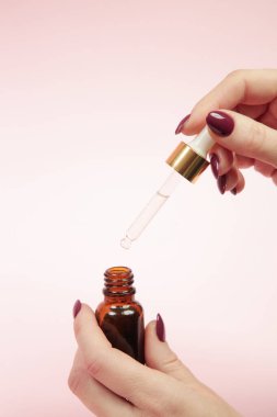Eller pipeti ve damlatan cam şişeyi yağlı tutsun. Doğal kozmetik, temel yağ, aromaterapi konsepti, cilt bakımı konsepti.