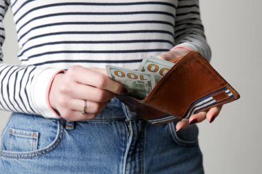 Cüzdanından 100 dolar sayan bir kadın.