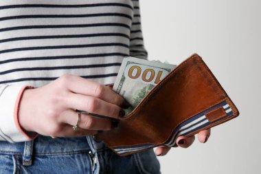 Cüzdanından 100 dolar sayan bir kadın.