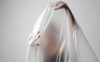 Plastik çarşafa sarılmış bir kadın. Stüdyo çekimi. Kadın ve ruh sağlığı konsepti.