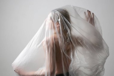 Plastik çarşafa sarılmış bir kadın. Stüdyo çekimi. Kadın ve ruh sağlığı konsepti.