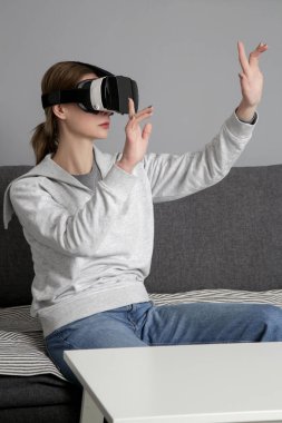Oturma odasında sanal gerçeklik gözlüklü kadın portresi. Sanal gerçeklik deneyimi ve gelecekteki teknoloji kavramı. 