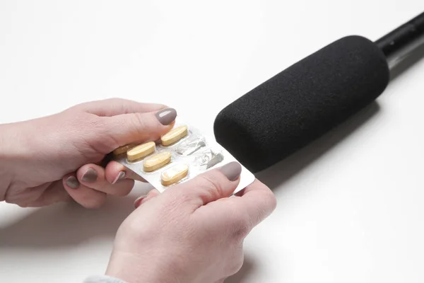 Asmrの音を作るためにマイクに錠剤パケットの箔やプラスチック製のクリンクを使用する女性 — ストック写真