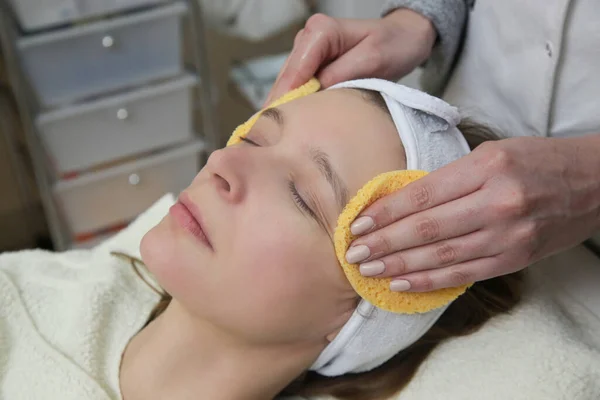皮膚科医は治療のために女性の顔の皮膚を準備します 剥離の工程 — ストック写真