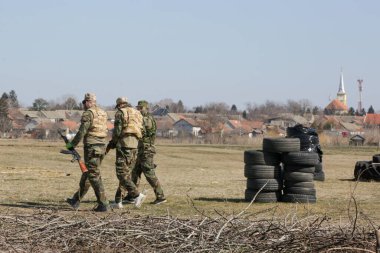 Askerler harabe köyde otomatik silahlarla bir hedefe ateş ediyorlar..