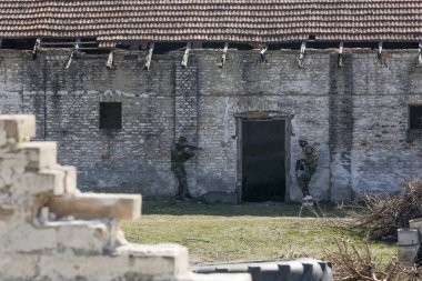 Askerler harabe köyde otomatik silahlarla bir hedefe ateş ediyorlar..