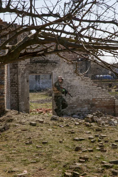 荒廃した村で自動兵器屋外で標的を撃つ兵士 — ストック写真