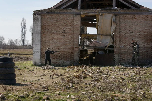 在被毁的村庄 士兵们在室外用自动武器射击一个目标 — 图库照片
