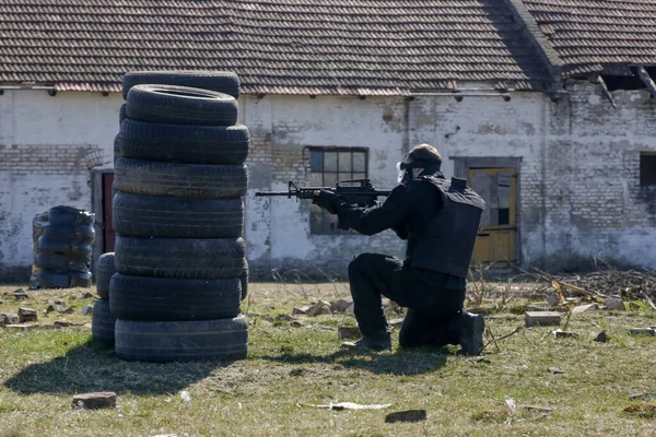 Soldiers shoot at a target with automatic weapons outdoor at ruined village.