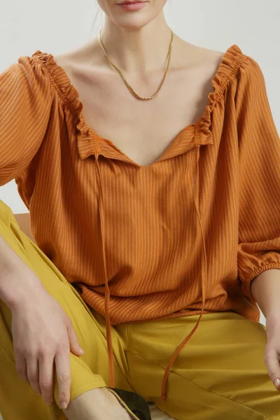 Keten elbise giyen kadın model, parlak turuncu bluz ve sarı pantolon. Stüdyo çekimi.