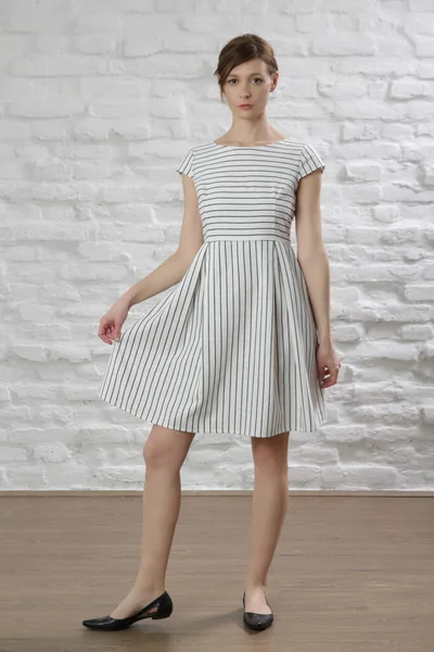 Çizgili pamuklu yaz elbisesi giymiş bir kadının stüdyo fotoğrafı..