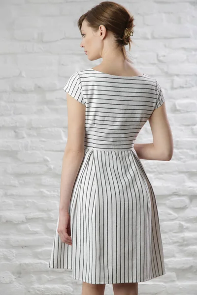 Çizgili pamuklu yaz elbisesi giymiş bir kadının stüdyo fotoğrafı..