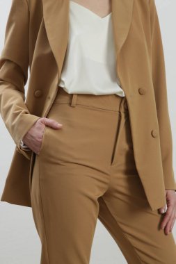 Bej takım elbiseli ve beyaz ipek bluzlu bir kadın model. Stüdyo çekimi.