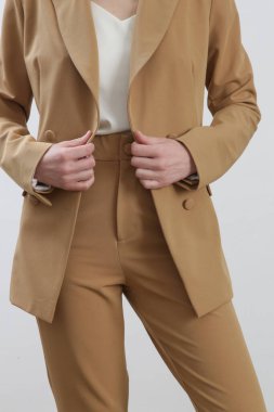 Bej takım elbiseli ve beyaz ipek bluzlu bir kadın model. Stüdyo çekimi.