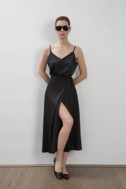 Beyaz gecelikli, ipek bluzlu ve siyah etekli bir kadın model. Klasik yaz modası. Stüdyo çekimi.