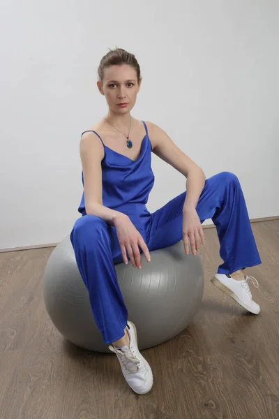 Woman in silk royal blue pants and camisole, studio shot.