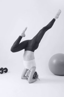 Yoga yapan genç fit bir kadının siyah beyaz fotoğrafları. Beyaz arkaplanda stüdyo görüntüsü.