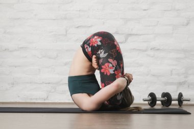 Yoga pozisyonlarını esneten genç bir kadın. Refah ve kendine bakım kavramı.