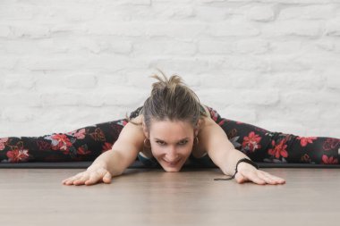Yoga pozisyonlarını esneten genç bir kadın. Önde derin bir yarık. Refah ve kendine bakım kavramı.