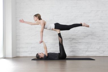 Stüdyoda Acro Yoga yapan iki genç kadın. Refah ve kendine bakım kavramı.