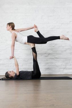 Stüdyoda Acro Yoga yapan iki genç kadın. Refah ve kendine bakım kavramı.