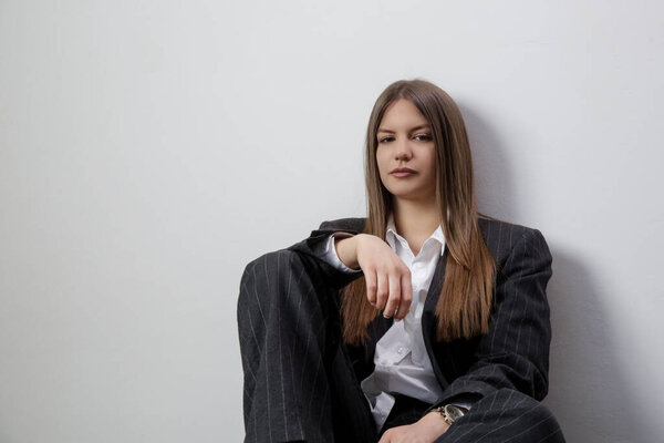 Студийный портрет модной девушки в белой рубашке и полосатом огромном костюме.