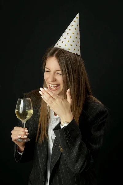 スタジオポートレートのファッショナブルな誕生日の女の子とともに誕生日帽子ホワイトワインのガラスを保持 — ストック写真