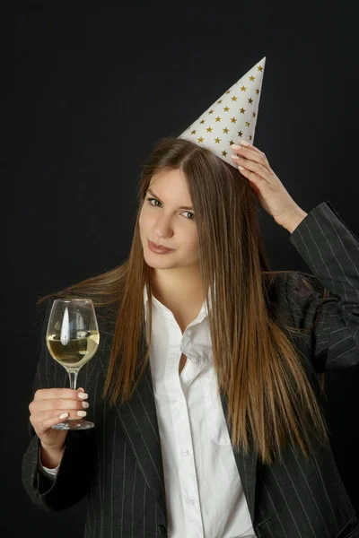 スタジオポートレートのファッショナブルな誕生日の女の子とともに誕生日帽子ホワイトワインのガラスを保持 — ストック写真