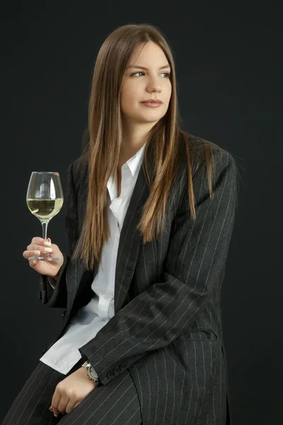 白ボタンダウンシャツと白ワインのガラスを保持ストライプ特大スーツでファッショナブルな女の子のスタジオポートレート — ストック写真