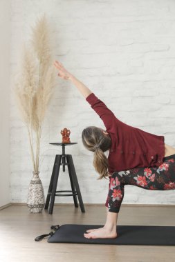 Yoga pozisyonlarını esneten genç bir kadın. Refah ve kendine bakım kavramı.