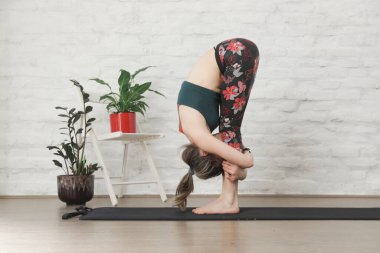 Yoga pozisyonlarını esneten genç bir kadın. Refah ve kendine bakım kavramı.