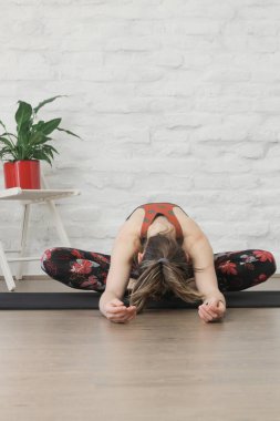 Yoga pozisyonlarını esneten genç bir kadın. Refah ve kendine bakım kavramı.