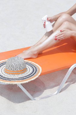 Bacaklarına güneş kremi süren bir kadın. Güneş koruma cildi konsepti.