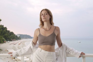 Young woman is standing on the balcony with a beautiful beach view