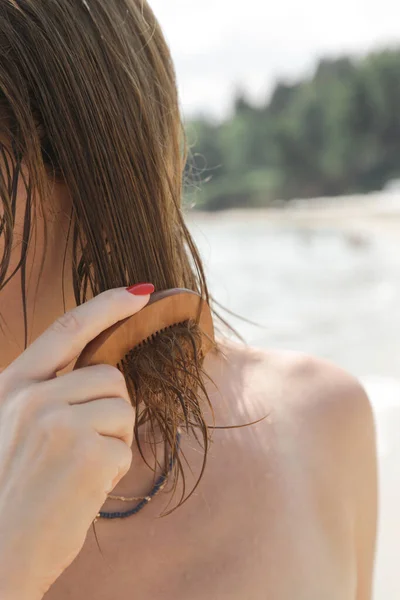 海滩上女人的头发女人用木制梳子贴着头发面罩 咸咸的海水和阳光造成的头发损害 夏季护发概念 — 图库照片