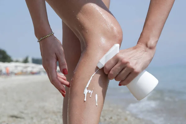 ビーチで日焼け止めクリームを足に塗る女性 太陽保護スキンケアコンセプト — ストック写真