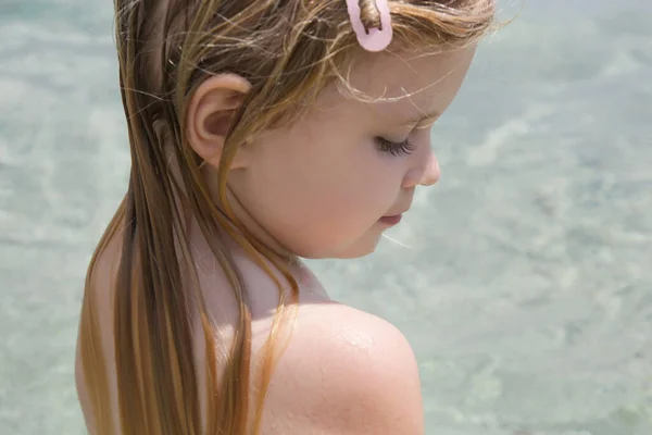 Child's long hair on the beach. Wet hair close up image. Hair damage due to salty ocean water and sun, summertime hair care concept.