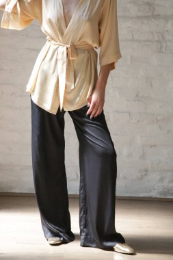 Studio serie of imges of young woman in beige silk robe and black wide trousers