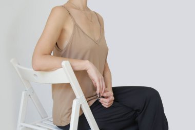 Female model wearing beige camisole cotton top and black trousers. Classic and simple summer fashion. Studio shot.