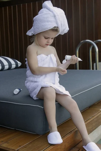 子供のためのスキンケア製品 小さな女の子は スキンケア製品を使用してタオルに包まれた — ストック写真