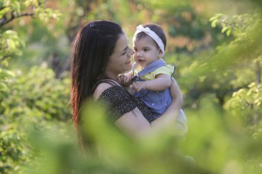 Genç anne, kızıyla dışarıda huzurlu bir yaz gününün tadını çıkarıyor. Parktaki aile fotoğrafı..